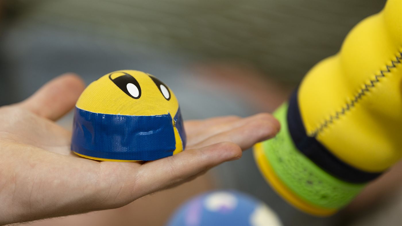 Der blaue Kopf liegt in der Handfläche, daneben der gelbe Körper der Maupe.